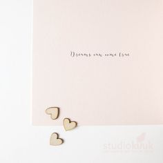 two wooden hearts sitting on top of a pink card with the words dreams come true