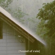 a white house with trees in the background and rain coming down on it's roof