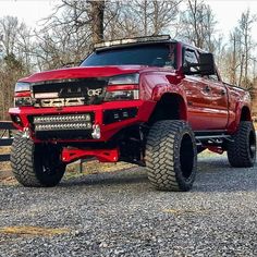 a red truck parked on top of a gravel road