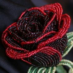 a red beaded rose sitting on top of a black jacket