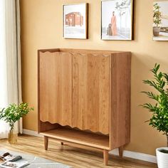 a wooden cabinet sitting in the corner of a living room next to a potted plant