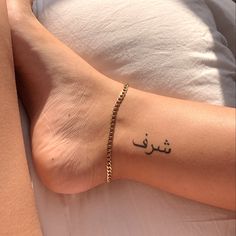 a woman's foot with arabic writing on it and a gold chain around her ankles