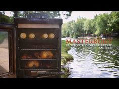 an old fashioned oven with some food in it next to a river and trees on the other side