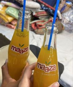 there are two bottles of orange juice with blue straws in each one, and the other is half full