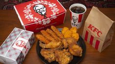 fried chicken and other foods on a plate next to two boxes of kfc coffee