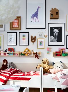 a child's bedroom with pictures on the wall and stuffed animals hanging above it