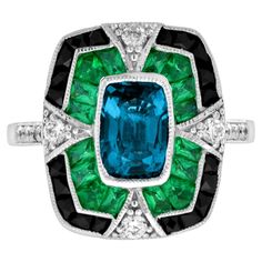 A striking and intriguing jewel, indeed. This bold and colorful Art Deco style ring highlights a gorgeous gleaming emerald cut London blue topaz framed in eye-catching contrast by French cut emerald and black onyx. Each side and shoulders set off with round diamond with milgrain edge. Ring Information Style: Edwardian Metal: 18K White Gold Weight: 6.50 g. (approx. total weight) Ring Size: US3-8 Center Gemstone Type: London Blue Topaz Shape: Octagon Size: 8 x 5.5 mm. Number: 1 Weight: 2.00 Carat Vintage Emerald Rings Blue Nile, Luxury Enamel Art Deco Rings, Luxury Blue Art Deco Rings, Gem Rings Stones 1stdibs, Edwardian Onyx Rings, Luxury Emerald Gemstones With Accent Stones, Luxury Multi-stone Emerald Cut Emerald Ring, Luxury Sapphire Ring With Emerald Cut And Gemstone Accents, Luxury Emerald-cut Sapphire Ring With Gemstone Accents