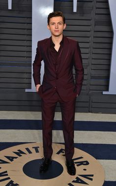 a man in a red suit standing on a blue and white striped floor with his hands in his pockets