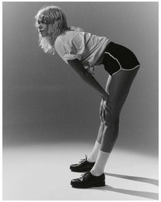 a black and white photo of a woman with her hands on her hips wearing shorts