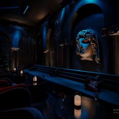 a dimly lit room with blue lighting and black walls, along with red velvet seats