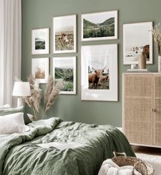 a bedroom with green walls and pictures on the wall above the bed, along with a wicker dresser