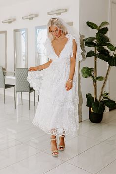 a woman in a white wedding dress standing on the floor with her veil over her head