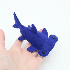 a hand holding a blue felt toy that looks like a fish