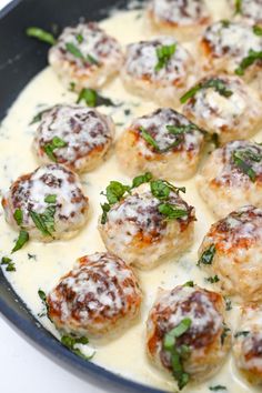 a pan filled with meatballs covered in sauce and parsley on top of it