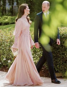 a man in a suit and tie walking next to a woman in a pink dress