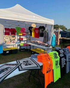 an outdoor tent with shirts on display for sale