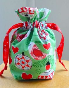 a green bag with red and white designs on it sitting on top of a wooden table