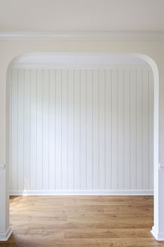 an empty room with white walls and wood floors