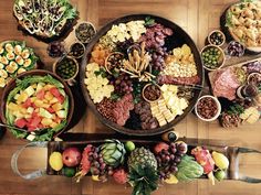 a variety of fruits and vegetables are arranged in bowls on a wooden table with knifes