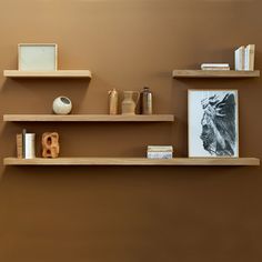 some shelves with pictures and vases on them against a brown wall in a living room