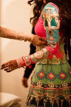 a woman in a green and red dress with her hands on her hips, holding onto the arm of another woman