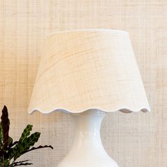 a white lamp sitting on top of a table next to a potted plant