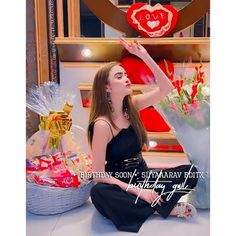 a woman is sitting on the floor in front of some flowers and presents with her hand