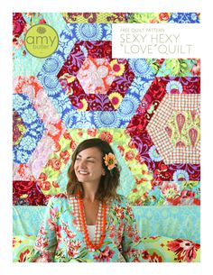 a woman sitting in front of a colorful quilt