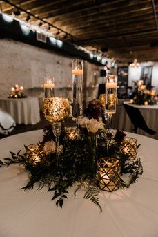 a table topped with candles and flowers on top of a white table cloth covered table