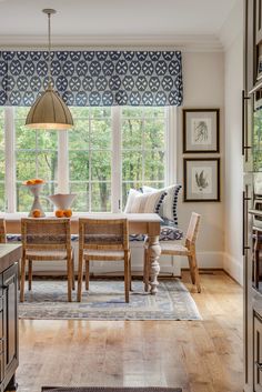 a dining room table and chairs in front of a window with blue roman shades on the windowsill