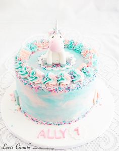 a birthday cake decorated with blue frosting and rainbow sprinkles on a white doily