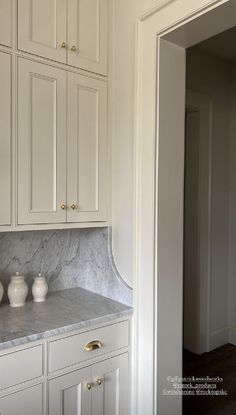 a kitchen with white cabinets and marble counter tops in the middle of it is shown