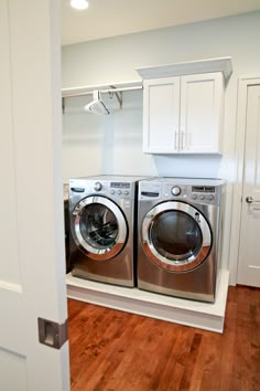 a washer and dryer in a room with white cabinets on the wall behind them