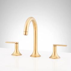 two gold faucets on a white surface