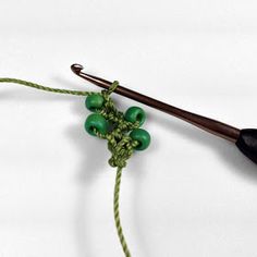 a crochet hook with green beads and a wooden knitting needle resting on it