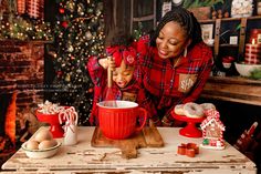 a woman and child in front of a christmas tree with presents on the table next to them