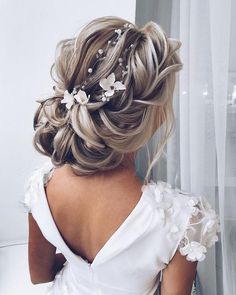 the back of a woman's head wearing a white dress with flowers in her hair