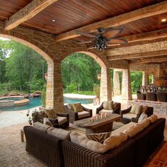 an outdoor living area with couches, tables and a pool in the back ground