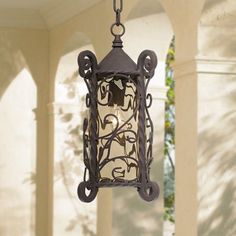 an outdoor light hanging from a chain on the outside of a house with columns and pillars