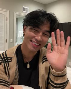 a man sitting at a table with his hand up in the air while making a peace sign