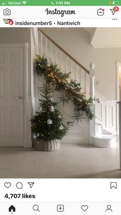 a christmas tree in the corner of a room next to a stair case with lights on it