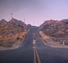 a woman standing in the middle of an empty road