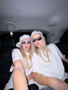 two women sitting in the back of a car with sunglasses on their heads and one wearing a white t - shirt