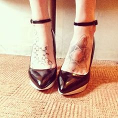 a woman's legs with tattoos on them and her black high heeled shoes