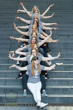 a group of young women sitting on top of steps with their hands in the air