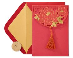 a red and yellow greeting card with a tasseled decoration on the front side