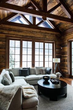 a living room with wood paneling and large windows in the ceiling, along with a sectional sofa