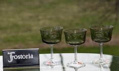 three wine glasses sitting on top of a glass table next to a sign that says trosteria