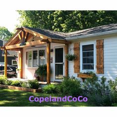 a small white house with wooden shutters on the front and side windows, covered by wood slats