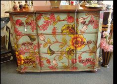 an old dresser with flowers painted on it's sides and some vases in the background